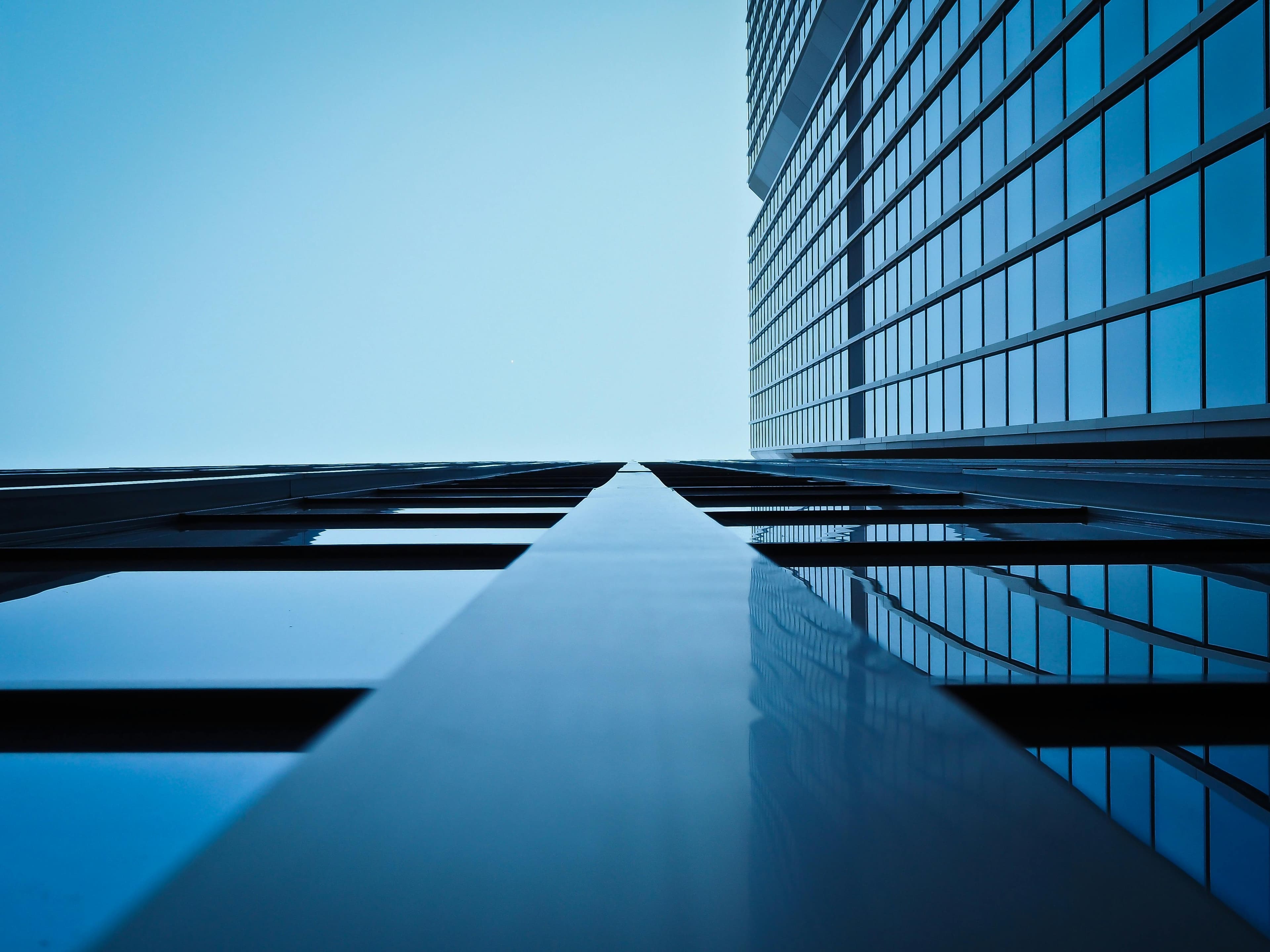 Low-angle view of a modern glass skyscraper against a blue sky